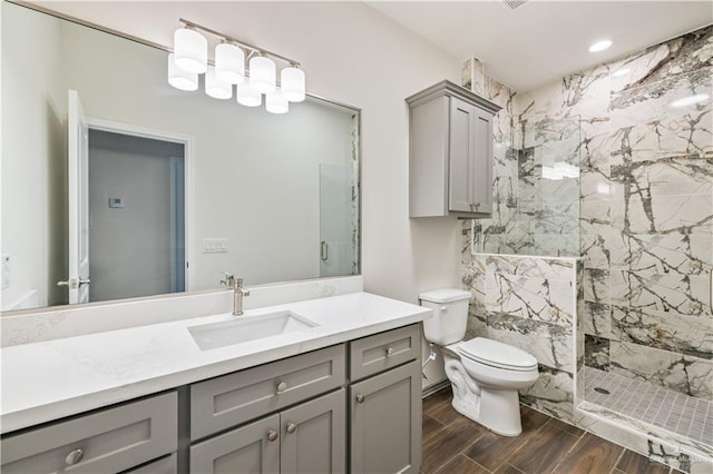 bathroom with wood tiled floor, tiled shower, vanity, and toilet