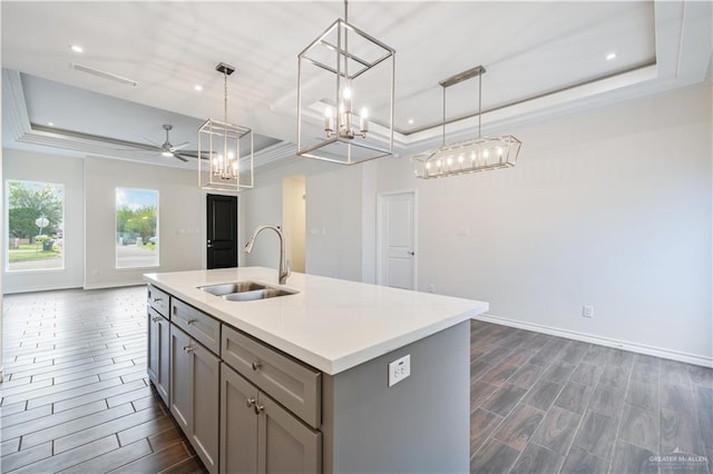 kitchen with open floor plan, a tray ceiling, gray cabinets, and a sink