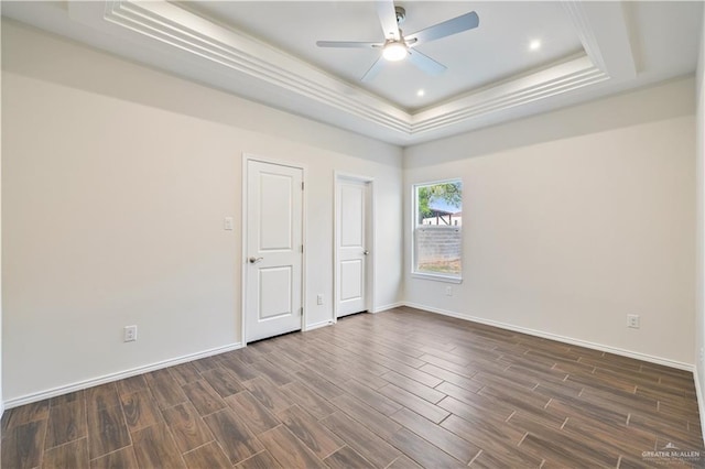 unfurnished room featuring a raised ceiling, dark wood finished floors, baseboards, and ceiling fan