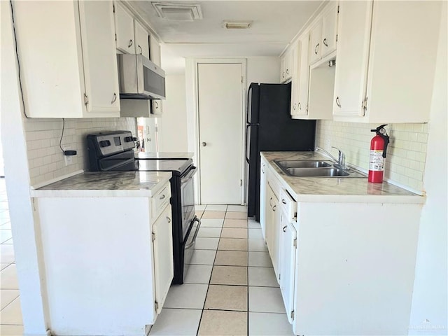 kitchen with stainless steel microwave, visible vents, electric range oven, light tile patterned flooring, and a sink