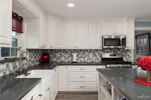 kitchen with sink, appliances with stainless steel finishes, dark hardwood / wood-style flooring, decorative backsplash, and white cabinets