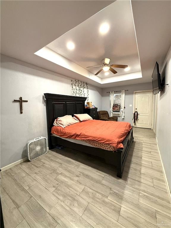 bedroom featuring a tray ceiling, ceiling fan, and light hardwood / wood-style floors