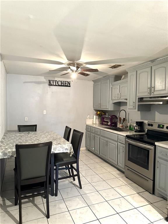 kitchen with gray cabinets, stainless steel electric range oven, sink, and a breakfast bar