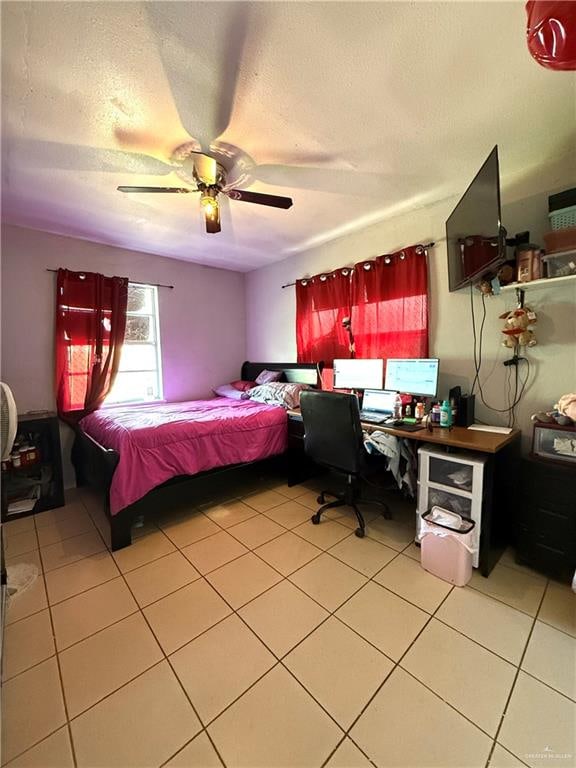 bedroom featuring ceiling fan, light tile patterned floors, and a textured ceiling