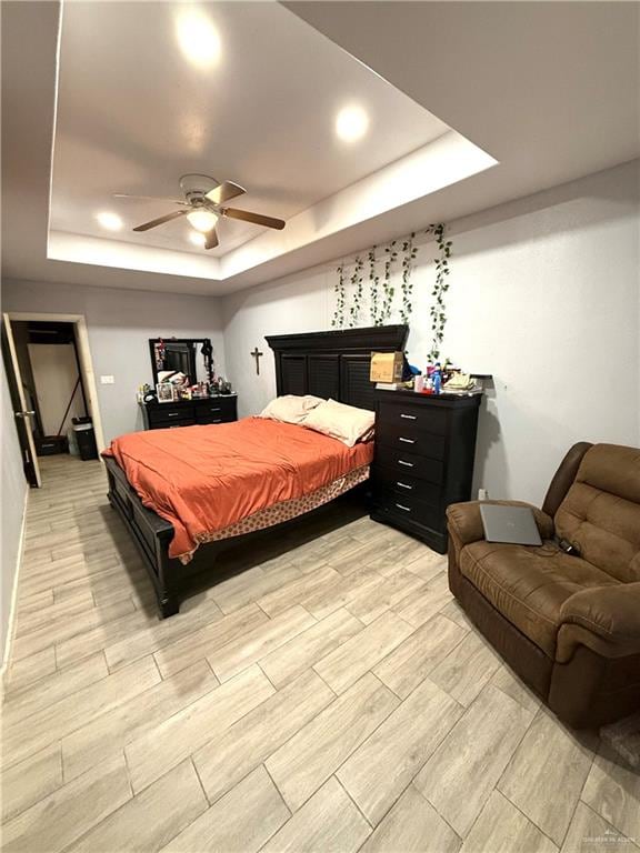 bedroom with a tray ceiling, light hardwood / wood-style flooring, and ceiling fan