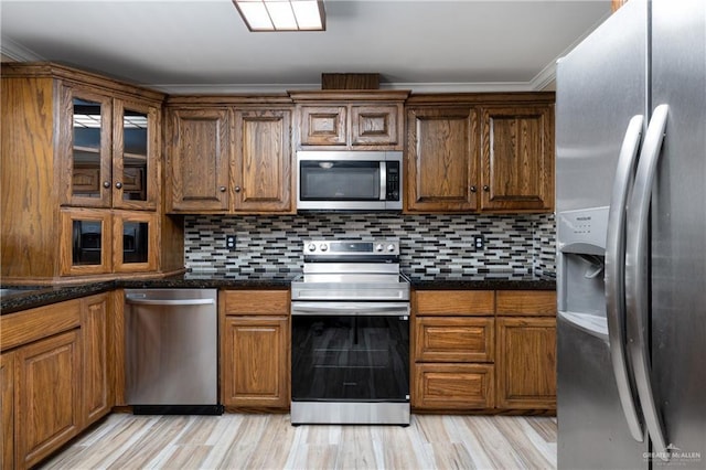 21890 Fm 508, Harlingen, TX 78550 - kitchen featuring stainless steel appliances, backsplash, glass insert cabinets, light wood-style flooring, and brown cabinets