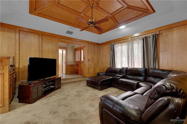 living room featuring light colored carpet, ceiling fan, coffered ceiling, and wood walls