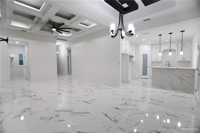 interior space with ceiling fan with notable chandelier, coffered ceiling, and sink