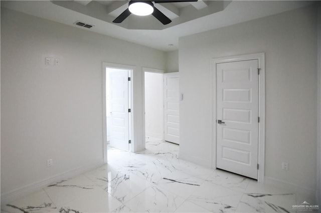 unfurnished room with ceiling fan and a raised ceiling