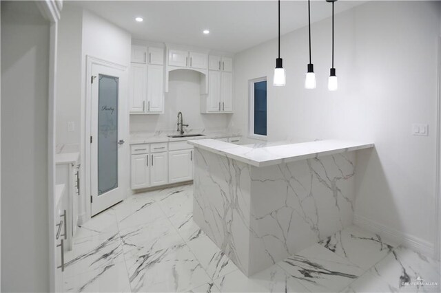 kitchen with white cabinets, light stone counters, and sink