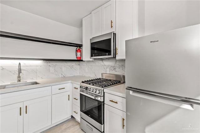 kitchen featuring sink, white cabinetry, stainless steel appliances, and tasteful backsplash