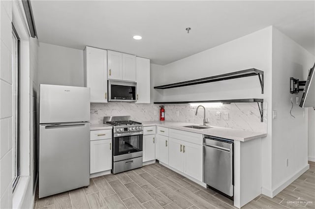 kitchen with backsplash, sink, stainless steel appliances, and white cabinetry