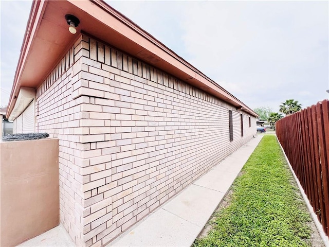 view of home's exterior with brick siding and fence