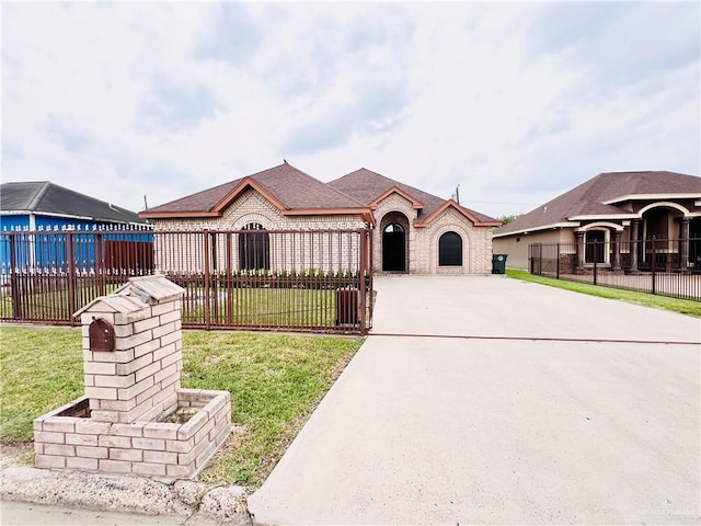 view of front facade with concrete driveway, brick siding, and a fenced front yard
