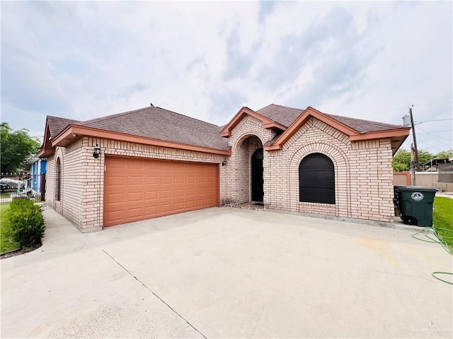 view of front of house featuring concrete driveway, an attached garage, brick siding, and roof with shingles