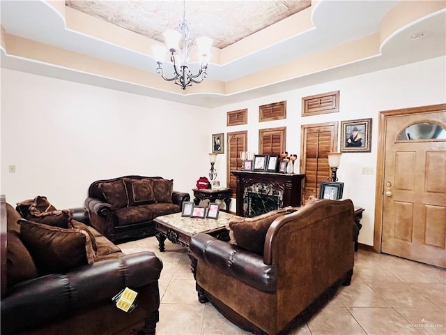 living area with a tray ceiling, an inviting chandelier, and light tile patterned flooring