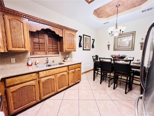 kitchen with a sink, a chandelier, backsplash, light countertops, and light tile patterned floors