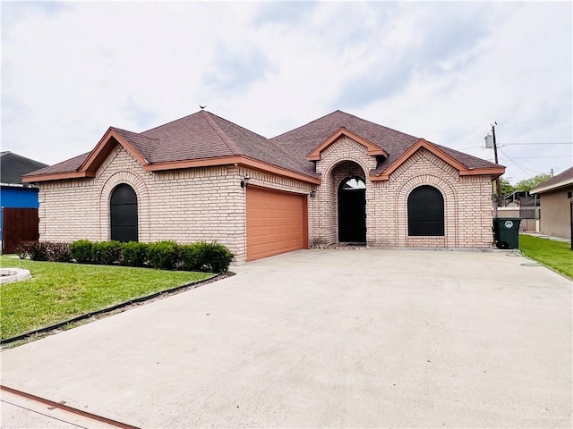 view of front of house featuring concrete driveway, a front lawn, an attached garage, brick siding, and roof with shingles