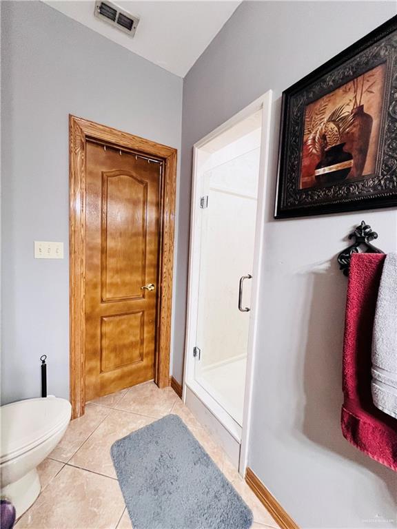 full bath with a shower stall, tile patterned flooring, visible vents, toilet, and baseboards
