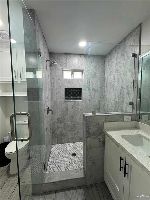 bathroom with vanity, toilet, and an enclosed shower