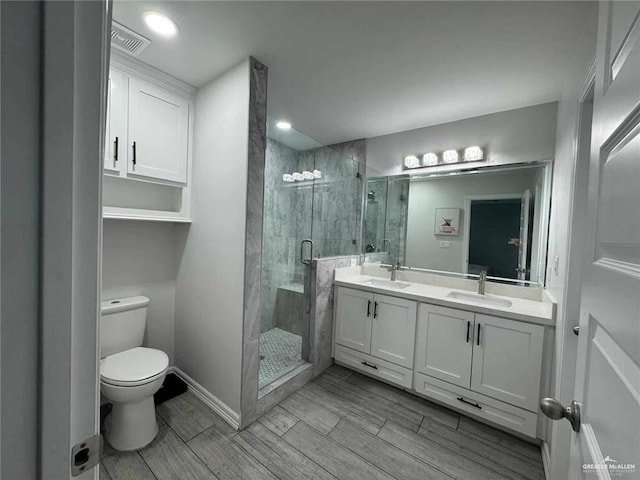 bathroom with vanity, a shower with shower door, and toilet