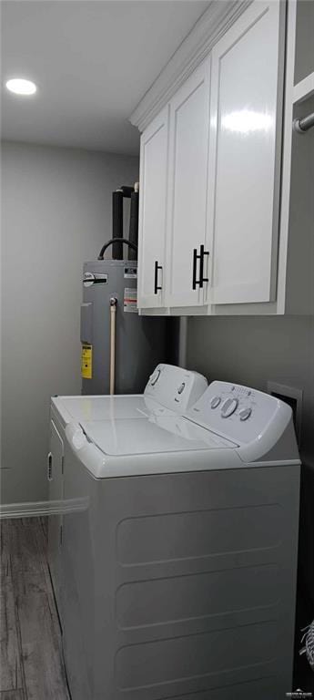 laundry area with water heater, dark hardwood / wood-style floors, cabinets, and washer and clothes dryer