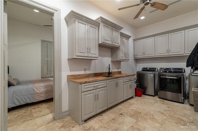 washroom with ceiling fan, recessed lighting, separate washer and dryer, a sink, and cabinet space