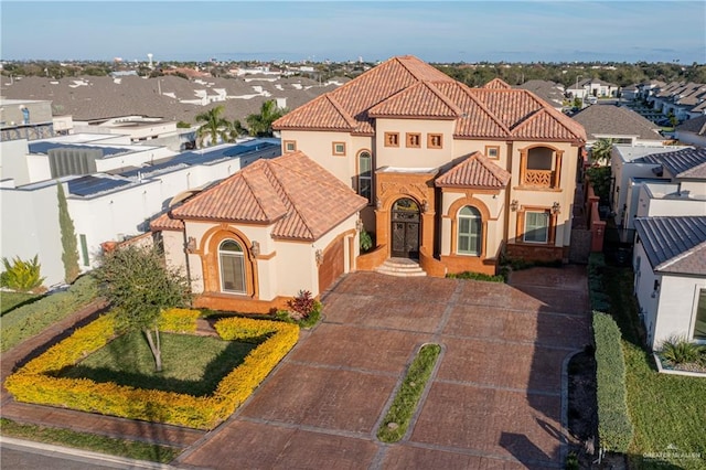 mediterranean / spanish-style home with a residential view, a tiled roof, and stucco siding