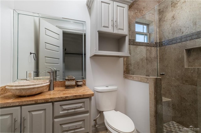 bathroom featuring a tile shower, vanity, and toilet