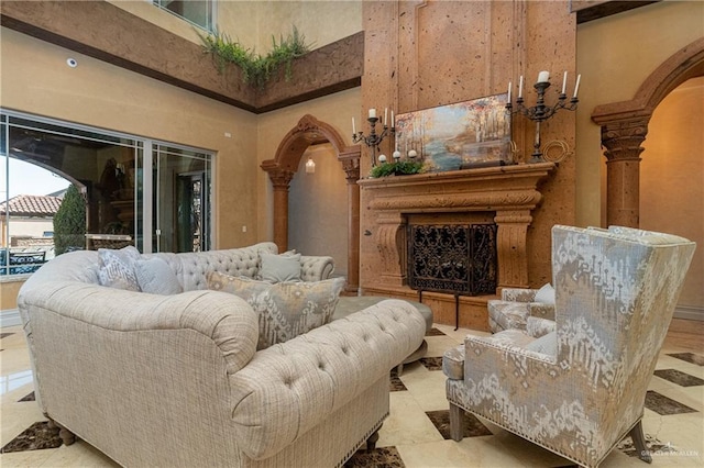 living room featuring arched walkways, a fireplace with raised hearth, and a towering ceiling