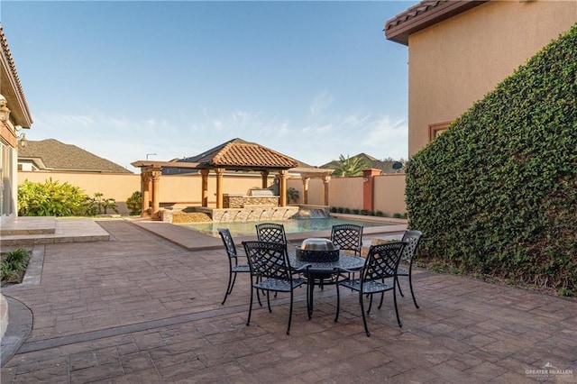 view of patio / terrace with outdoor dining space, fence, a fenced in pool, and a gazebo