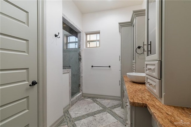 bathroom with a shower stall, vanity, and baseboards