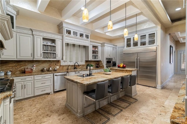 kitchen with open shelves, tasteful backsplash, appliances with stainless steel finishes, a kitchen island with sink, and a sink