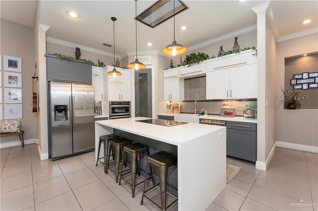 kitchen featuring pendant lighting, stainless steel appliances, light countertops, white cabinetry, and a kitchen island