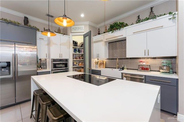 kitchen featuring a center island, pendant lighting, light countertops, appliances with stainless steel finishes, and white cabinetry