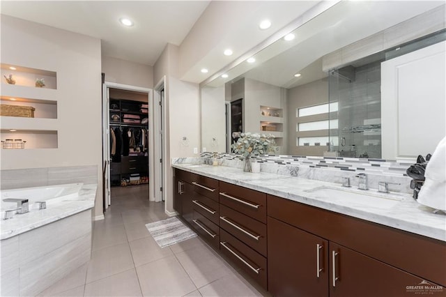 full bath with double vanity, a stall shower, tile patterned floors, a walk in closet, and a sink