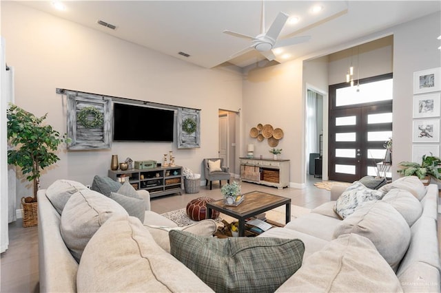 living room featuring ceiling fan, light tile patterned floors, a high ceiling, visible vents, and french doors