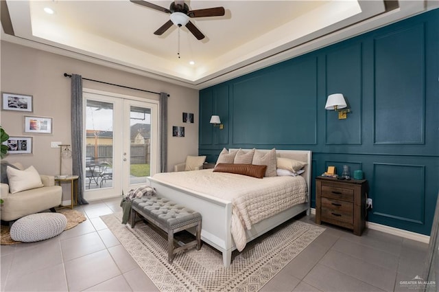 bedroom featuring access to exterior, tile patterned floors, a decorative wall, and a raised ceiling