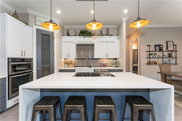 kitchen with a center island, light countertops, white cabinetry, a kitchen breakfast bar, and black electric cooktop