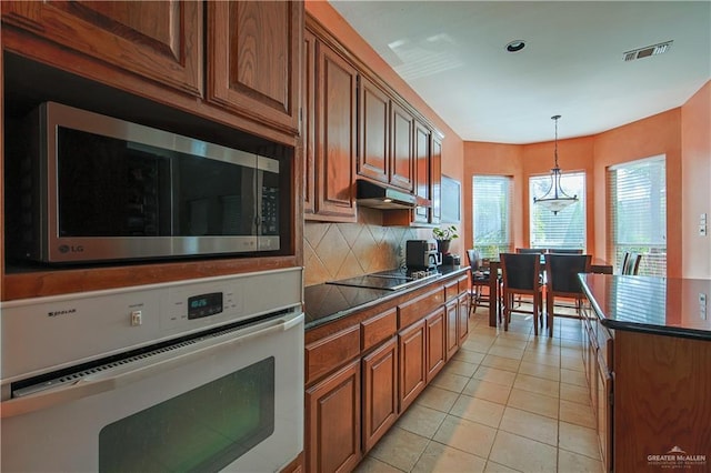 kitchen featuring backsplash, oven, pendant lighting, black electric stovetop, and light tile patterned floors