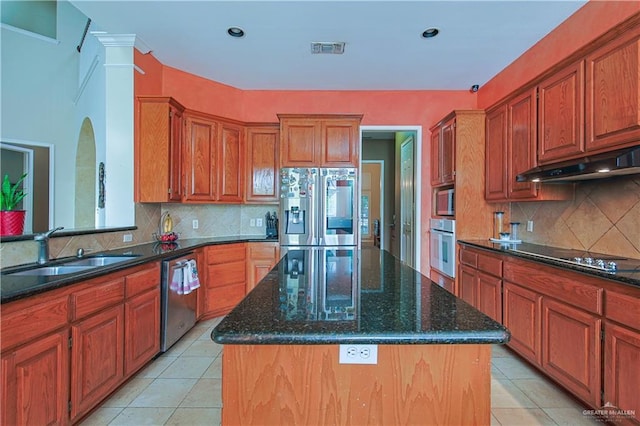 kitchen with light tile patterned flooring, sink, a kitchen island, and stainless steel appliances