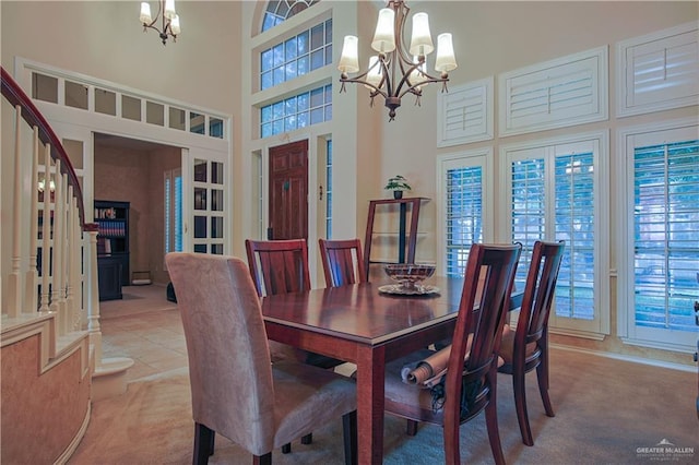 dining area featuring a towering ceiling, light colored carpet, and an inviting chandelier