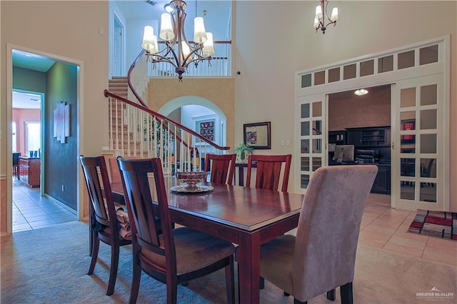 tiled dining space with french doors, a towering ceiling, and an inviting chandelier