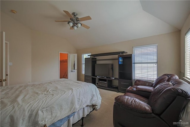 bedroom with ceiling fan, a spacious closet, light colored carpet, vaulted ceiling, and a closet