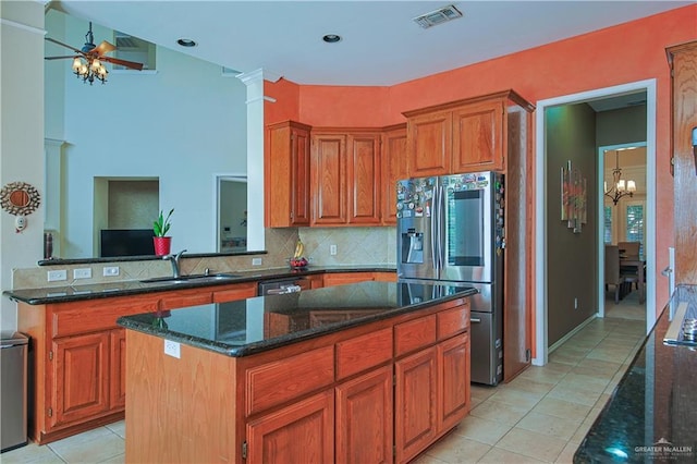 kitchen featuring appliances with stainless steel finishes, backsplash, ceiling fan with notable chandelier, sink, and a center island