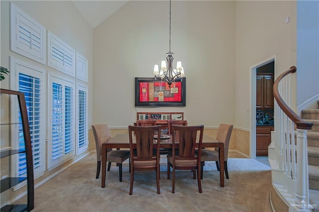 dining area with light colored carpet, vaulted ceiling, and an inviting chandelier