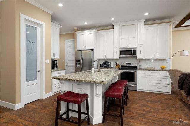 1408 May Dr, Edinburg, TX 78539 - kitchen with tasteful backsplash, white cabinets, appliances with stainless steel finishes, a breakfast bar, and crown molding
