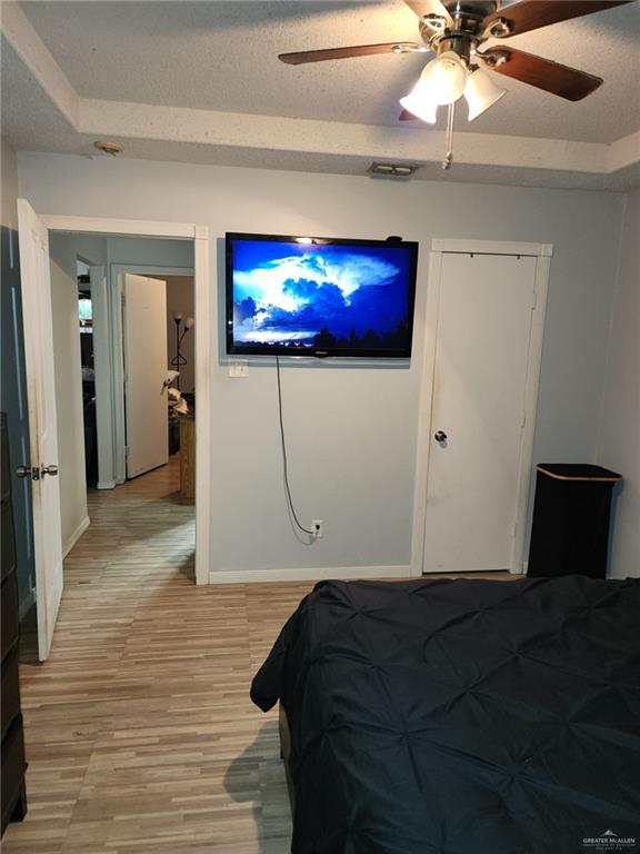 bedroom with ceiling fan, a textured ceiling, and light hardwood / wood-style floors