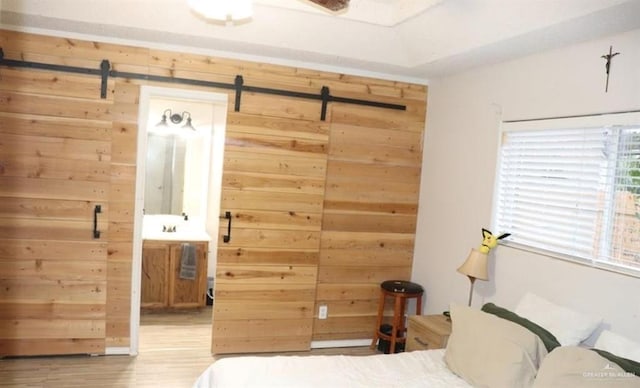 unfurnished bedroom with light hardwood / wood-style flooring, wooden walls, and a barn door