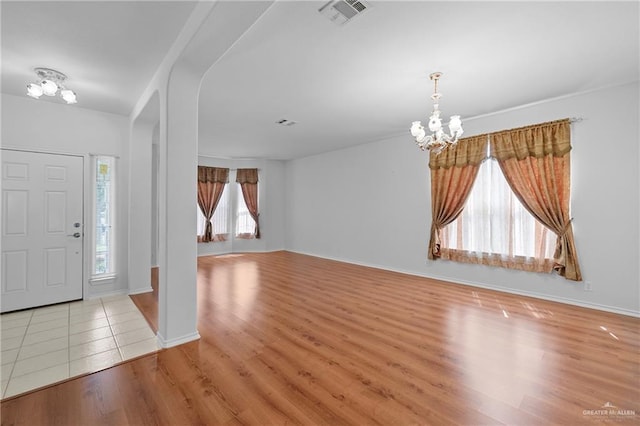 foyer entrance with a chandelier, visible vents, baseboards, and wood finished floors